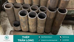 Các đoạn thép ống đúc siêu dày đã được cắt ngắn và xếp nằm ngang trên sàn bê tông, lộ rõ phần thịt ống dày và bề mặt vỏ thép màu vàng gỉ